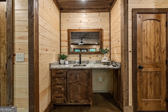 bar with wood walls, sink, ceiling fan, and stone countertops