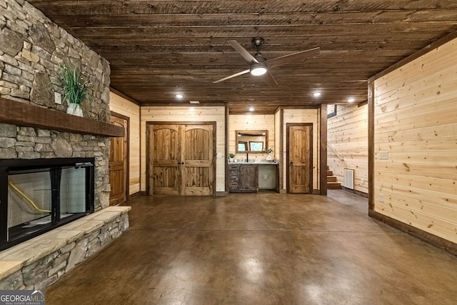 unfurnished living room featuring ceiling fan, wooden ceiling, and wood walls