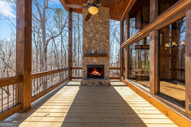 deck featuring an outdoor stone fireplace and ceiling fan