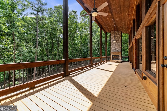 wooden terrace featuring ceiling fan and an outdoor stone fireplace