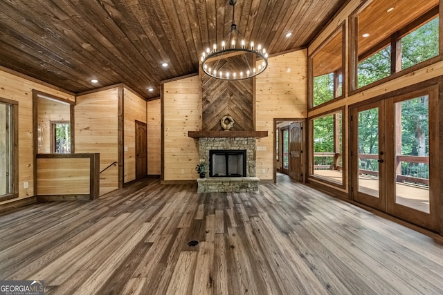 unfurnished living room featuring hardwood / wood-style flooring, a stone fireplace, wooden ceiling, and wooden walls