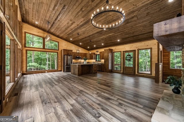 unfurnished living room with wooden ceiling, dark wood-type flooring, an inviting chandelier, high vaulted ceiling, and wood walls