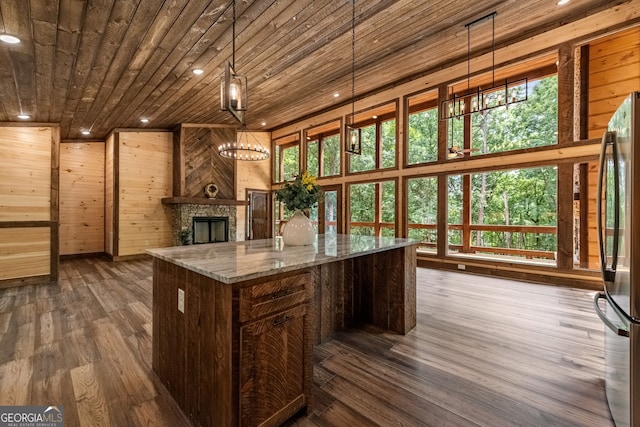 kitchen featuring stainless steel fridge, pendant lighting, light stone counters, and a healthy amount of sunlight