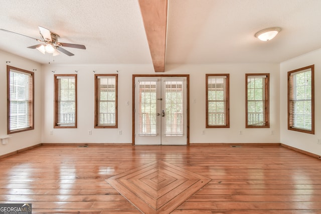 interior space featuring beamed ceiling, plenty of natural light, ceiling fan, and a textured ceiling