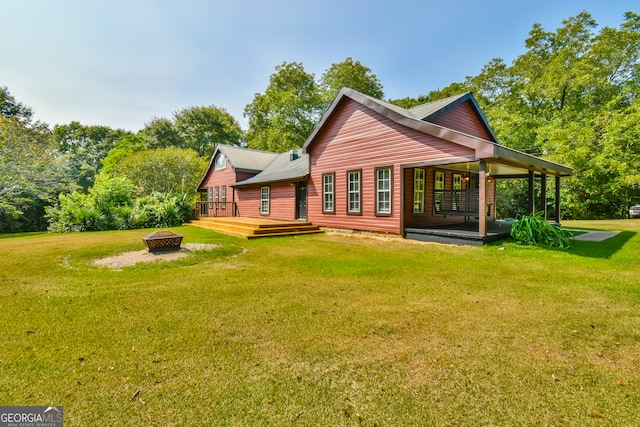 rear view of house with an outdoor fire pit, a yard, and a patio