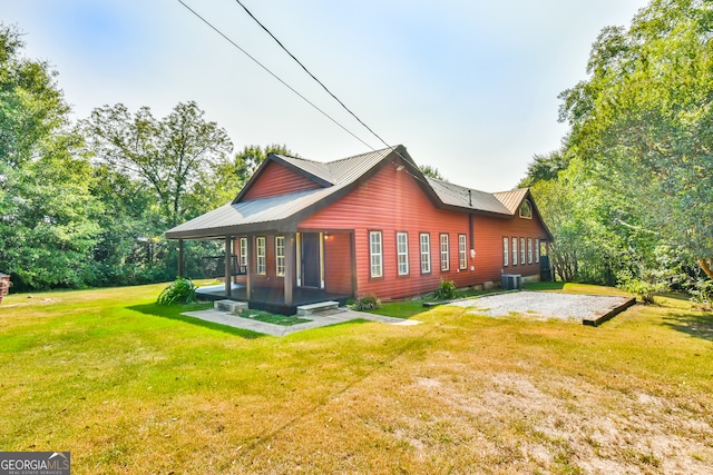 rear view of house featuring a lawn and central AC