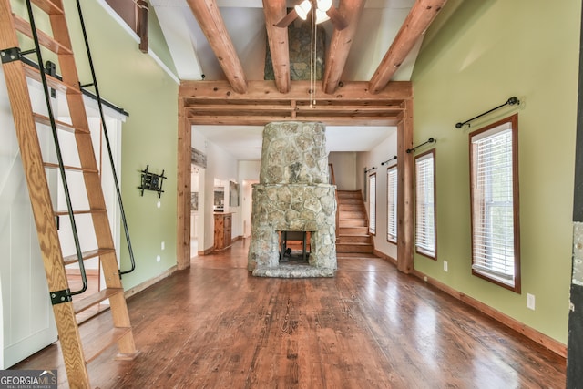 unfurnished living room featuring a fireplace, hardwood / wood-style floors, beam ceiling, and ceiling fan