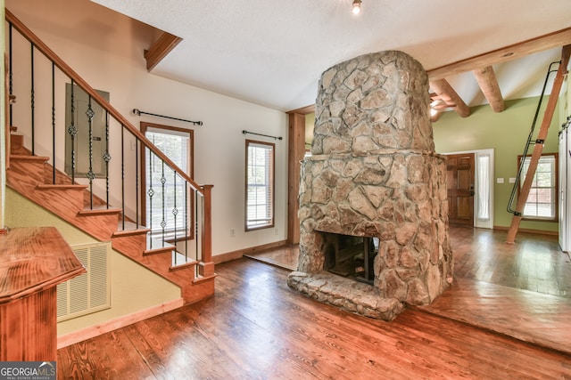 interior space featuring hardwood / wood-style floors, a fireplace, lofted ceiling with beams, and a textured ceiling