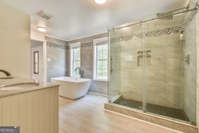 bathroom with plus walk in shower, vanity, and hardwood / wood-style floors