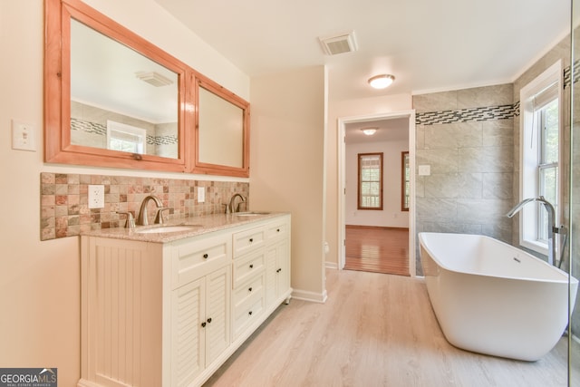 bathroom featuring vanity, a bath, and wood-type flooring