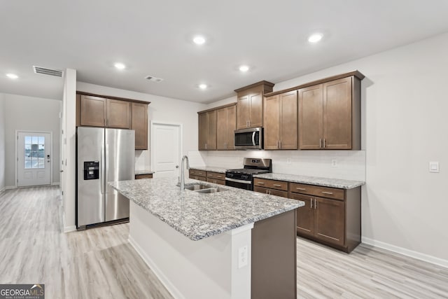 kitchen featuring a kitchen island with sink, sink, tasteful backsplash, light hardwood / wood-style floors, and stainless steel appliances