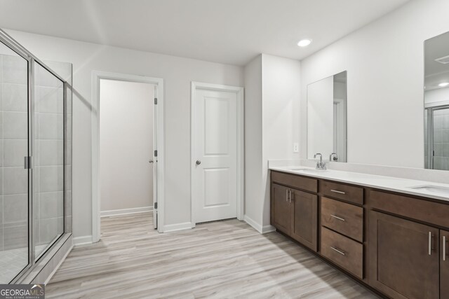 bathroom featuring vanity, hardwood / wood-style flooring, and a shower with shower door