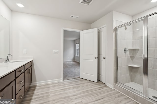 bathroom with vanity, hardwood / wood-style flooring, and a shower with door