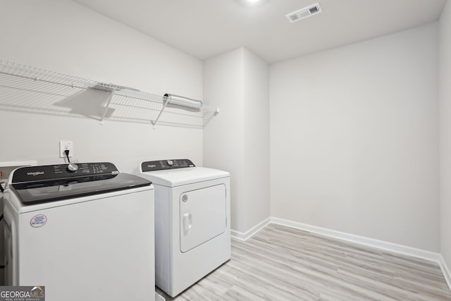 laundry room featuring washer and dryer and light hardwood / wood-style floors