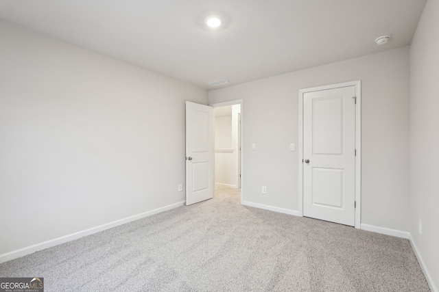 unfurnished bedroom with light carpet and a closet