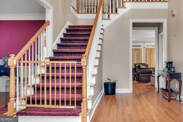stairs with ornamental molding, baseboards, and wood finished floors