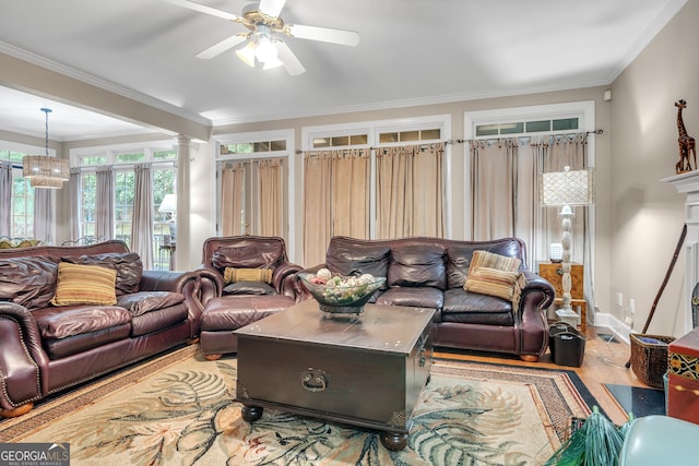 living room featuring ceiling fan with notable chandelier, wood finished floors, ornamental molding, and decorative columns