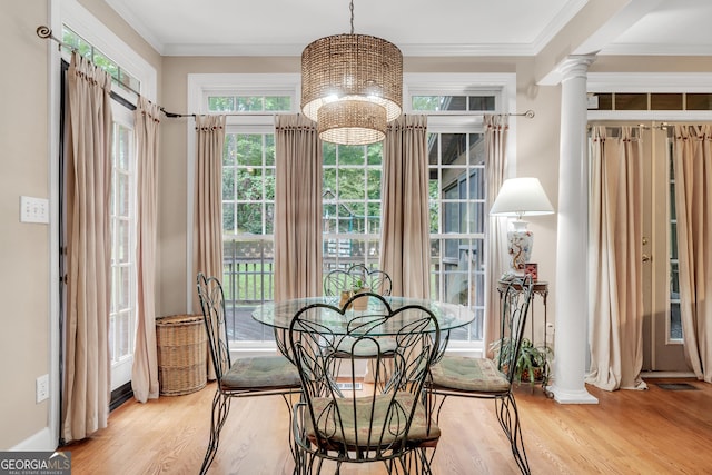 dining room featuring decorative columns, an inviting chandelier, ornamental molding, and wood finished floors