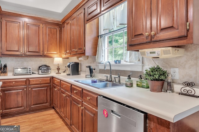 kitchen featuring brown cabinetry, light wood-style floors, dishwasher, and a sink