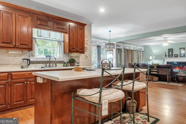 kitchen with light wood-style flooring, a center island, a sink, and a breakfast bar