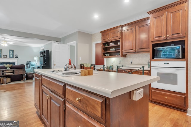 kitchen with white oven, a center island, open shelves, backsplash, and light wood-style flooring