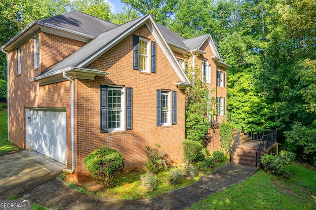 view of side of property featuring a garage, roof with shingles, brick siding, and driveway