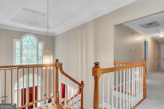 stairs featuring a notable chandelier, ornamental molding, visible vents, a raised ceiling, and carpet