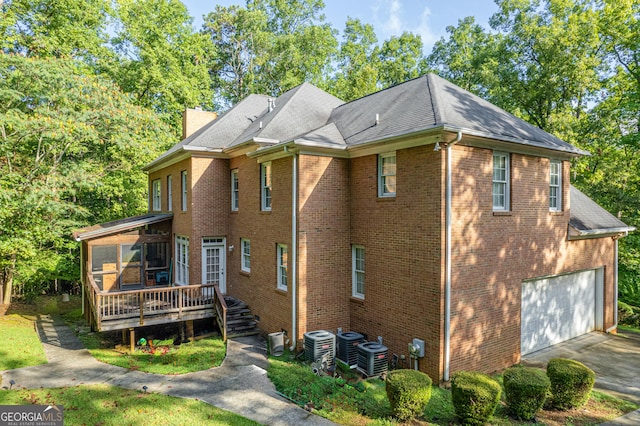 view of home's exterior with aphalt driveway, a sunroom, cooling unit, brick siding, and a garage