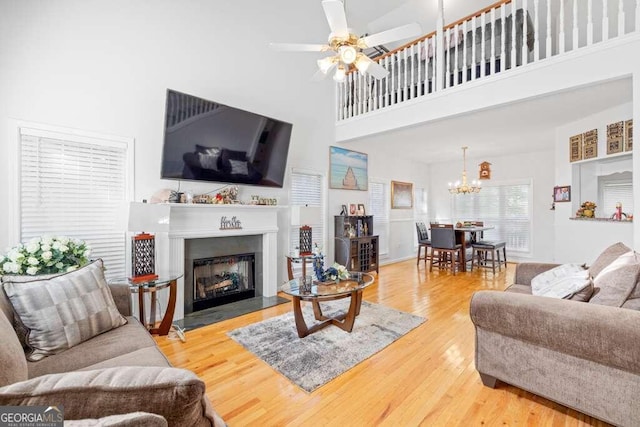 living room with a high ceiling, hardwood / wood-style floors, and ceiling fan with notable chandelier