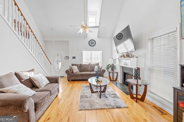 living room featuring a high end fireplace, high vaulted ceiling, hardwood / wood-style flooring, and ceiling fan