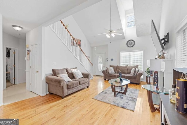 living room with ceiling fan, hardwood / wood-style floors, high vaulted ceiling, and a fireplace