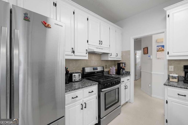 kitchen featuring tasteful backsplash, stainless steel appliances, dark stone counters, and white cabinetry