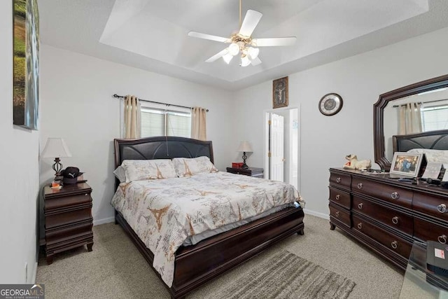 bedroom with a tray ceiling, ceiling fan, and light carpet