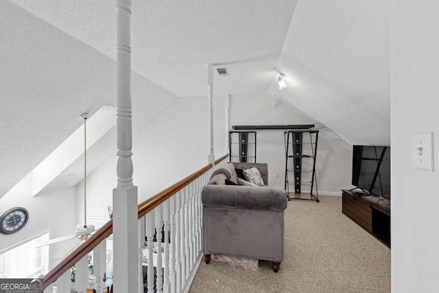 living area with vaulted ceiling, a textured ceiling, and carpet