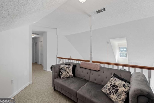 living room with a textured ceiling, light colored carpet, and ceiling fan