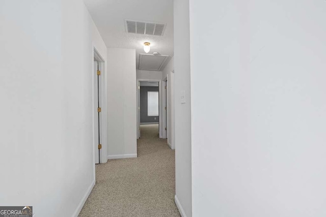 hall featuring a textured ceiling and light colored carpet