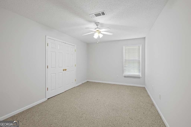 unfurnished bedroom with a textured ceiling, ceiling fan, and carpet