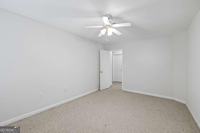 carpeted empty room featuring ceiling fan and a textured ceiling