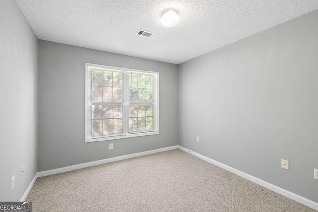 carpeted empty room with a textured ceiling