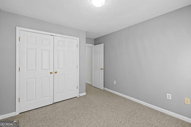 unfurnished bedroom with a textured ceiling, carpet floors, and a closet