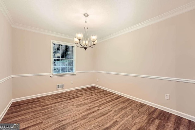 empty room featuring crown molding, wood-type flooring, and a chandelier