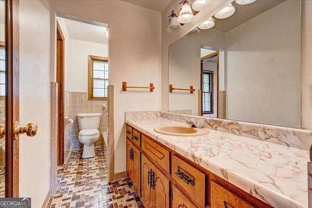 bathroom featuring vanity, toilet, and tile walls