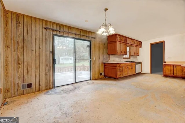 kitchen featuring stainless steel dishwasher, decorative light fixtures, sink, an inviting chandelier, and wooden walls