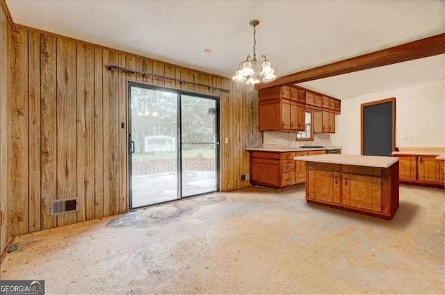 kitchen with kitchen peninsula, decorative light fixtures, a notable chandelier, wooden walls, and beamed ceiling