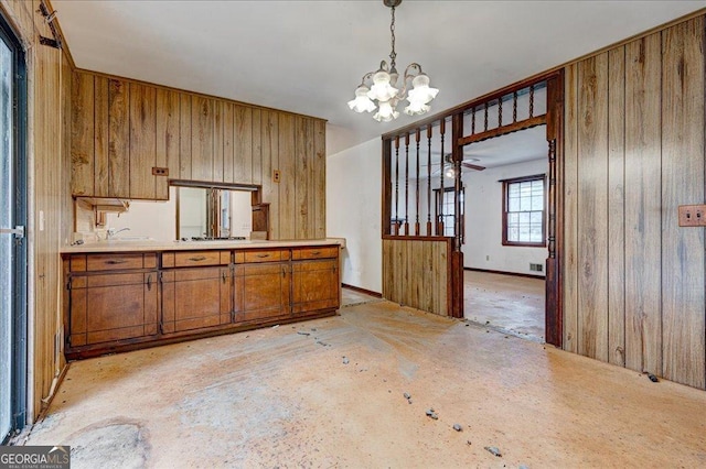 kitchen featuring wooden walls, an inviting chandelier, and pendant lighting