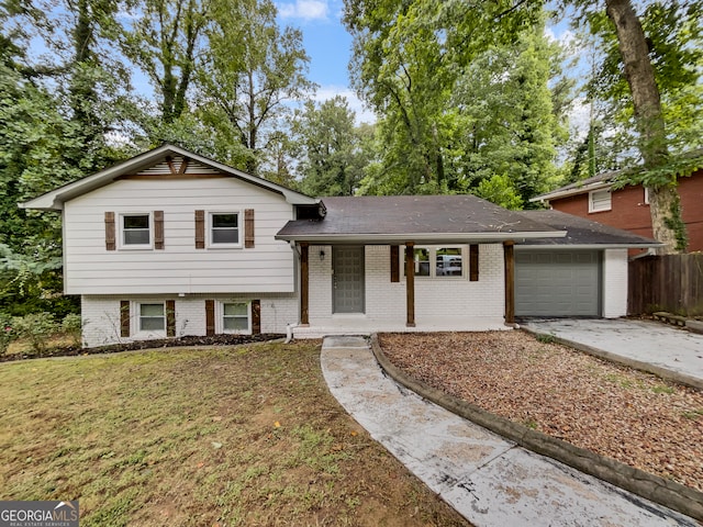 tri-level home featuring a garage, a front lawn, and covered porch