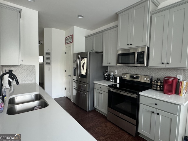 kitchen featuring sink, gray cabinetry, stainless steel appliances, backsplash, and dark hardwood / wood-style flooring