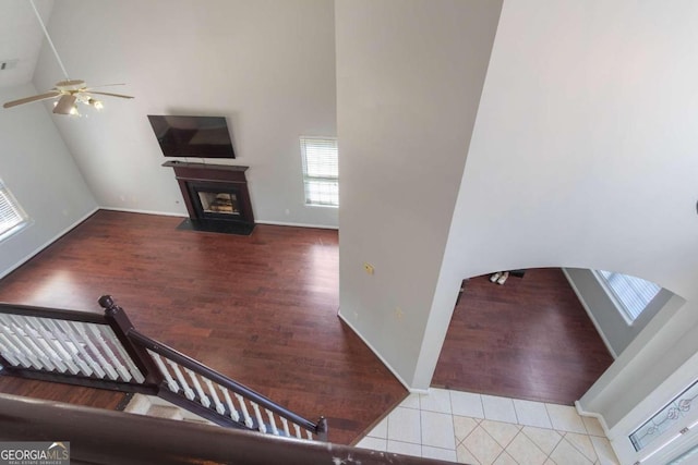 interior space featuring a towering ceiling, ceiling fan, and hardwood / wood-style flooring