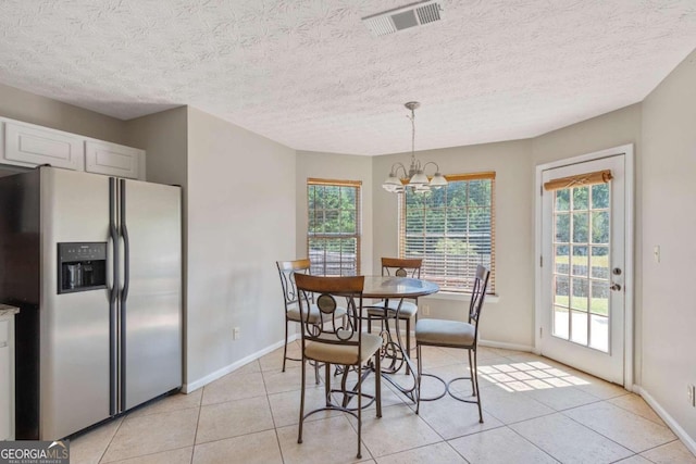 tiled dining area with an inviting chandelier, a textured ceiling, and a wealth of natural light