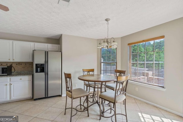 tiled dining area featuring a textured ceiling and a chandelier